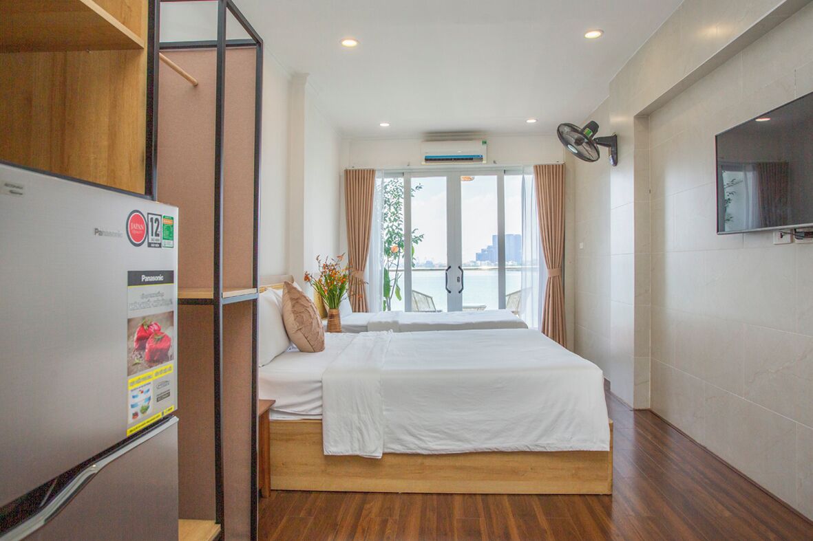 A hotel room with a bed, a TV mounted on the wall, and a window with curtains.