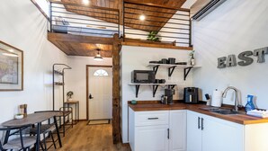 A compact kitchen with white cabinets, a wooden countertop, and a built-in microwave. - Charming Tiny Home Cottage - East Side! (Austin)