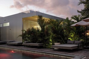 A modern outdoor pool area with lounge chairs and a large bed. - UNIT SPACE VILLAGE (Tabanan)