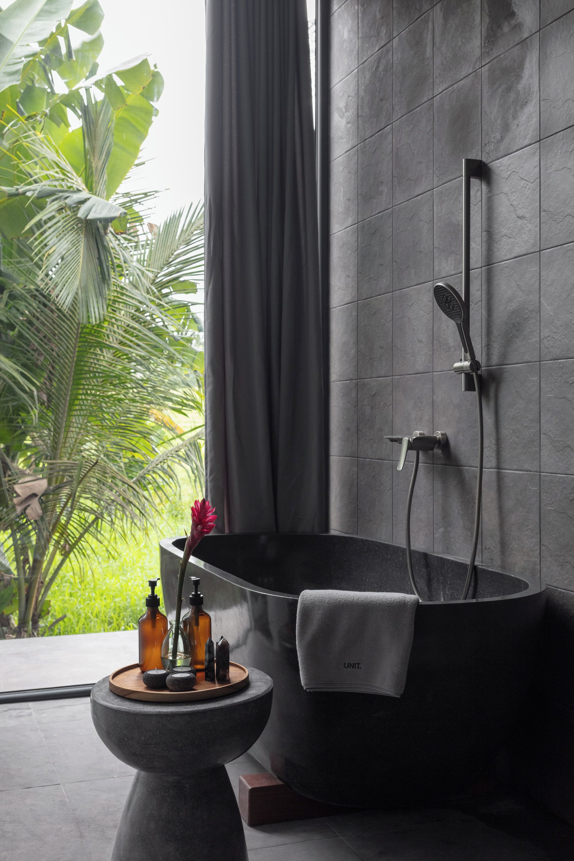 Casa de banho moderna com uma banheira independente, chuveiro e um lavatório pedestal pequeno com produtos de higiene pessoal.