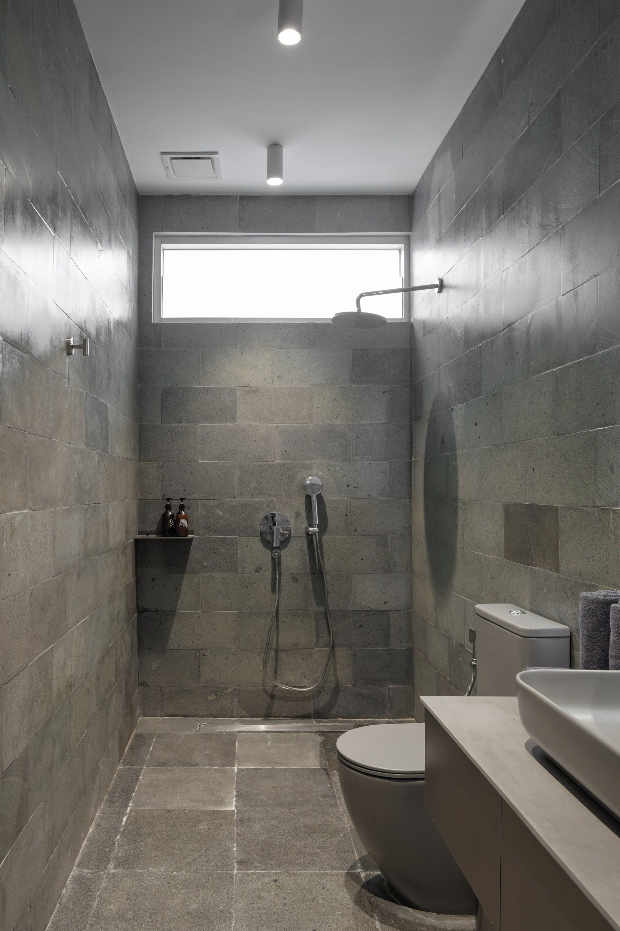 A modern bathroom with a shower, toilet, and sink.