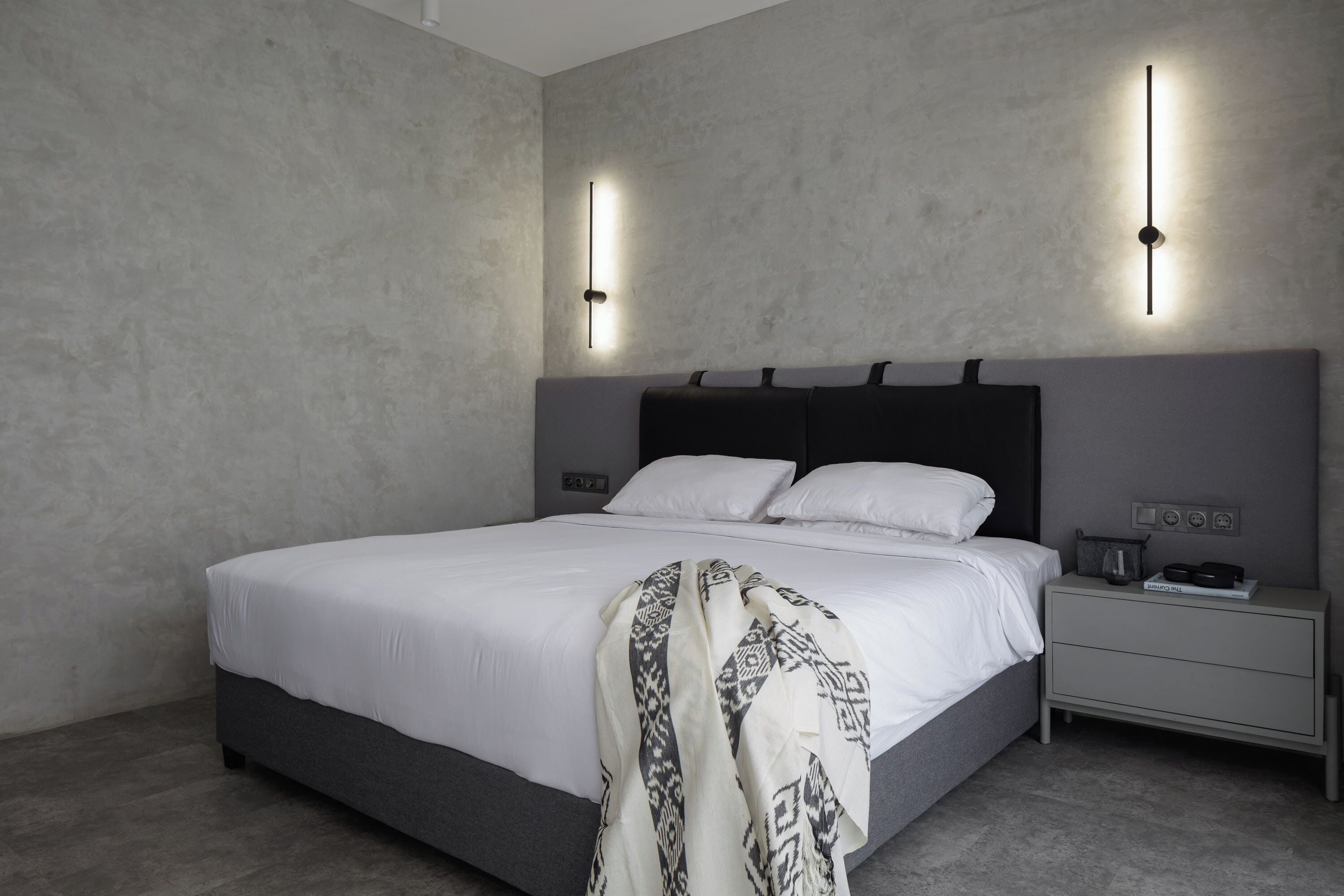 A modern bedroom with a large bed, a bedside table, and a nightstand.