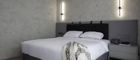 A modern bedroom with a large bed, a bedside table, and a nightstand.