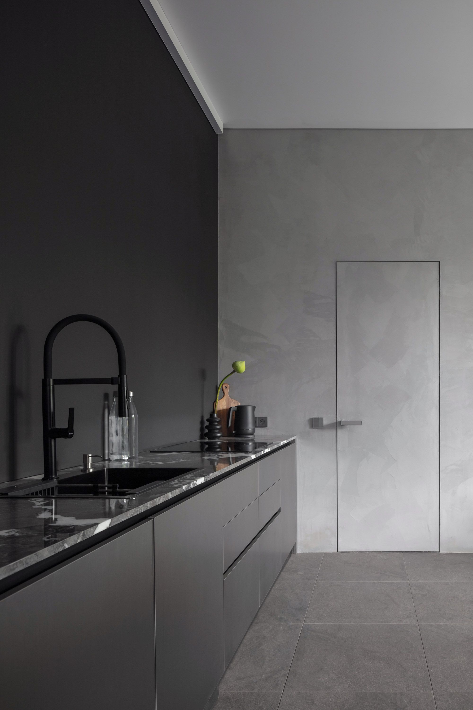 Une cuisine moderne avec un plan de travail foncé, un robinet noir et un design minimaliste.