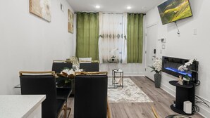 Un salon moderne avec un canapé, des fauteuils, un téléviseur et une petite table sur laquelle est posée une plante.