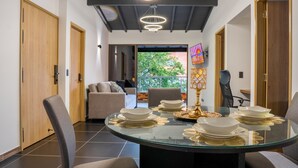 A modern dining area with a glass table set for six, surrounded by chairs.