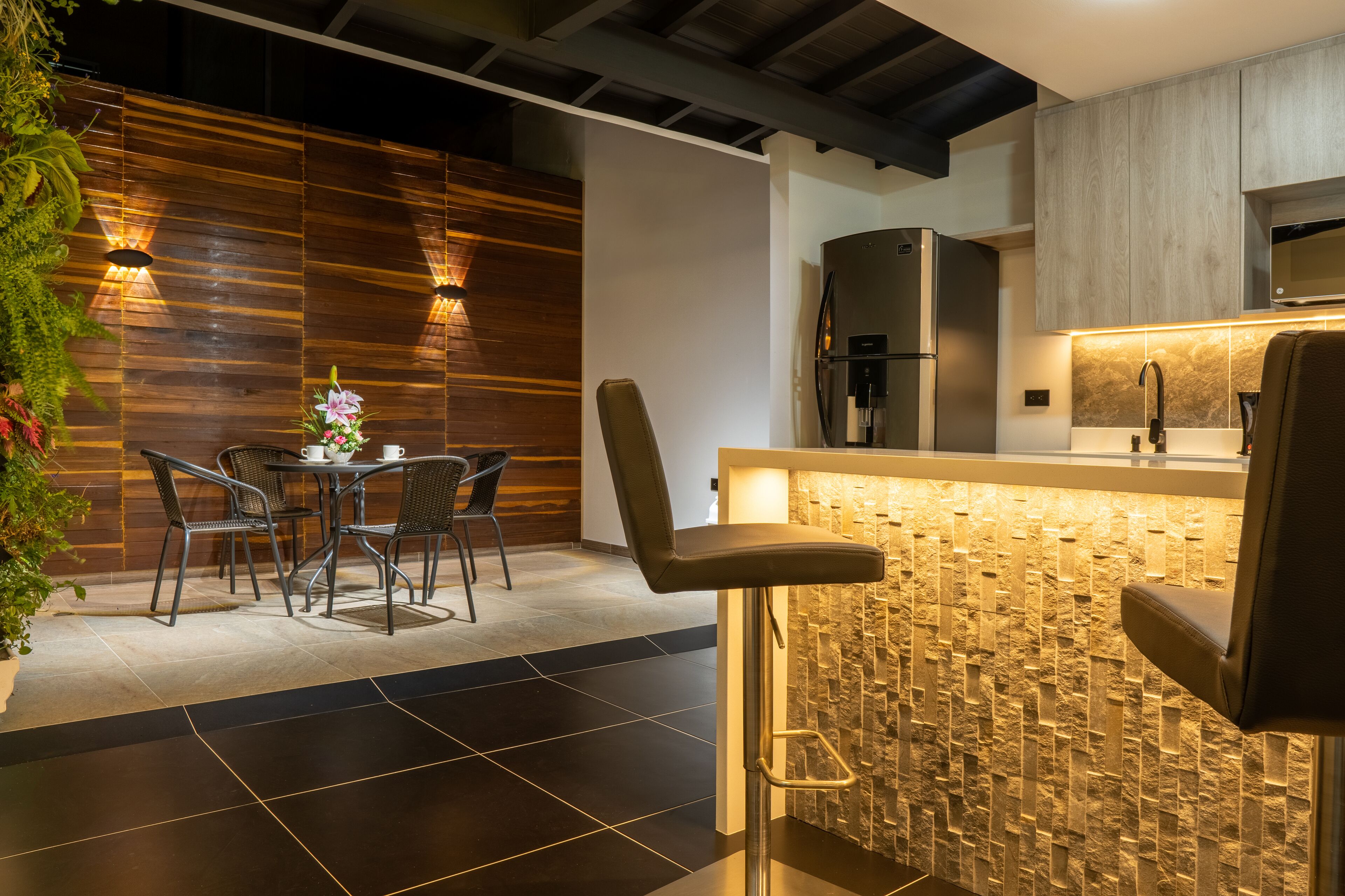 Una cocina moderna con salpicadero de piedra, un refrigerador de acero inoxidable y una barra con mostrador alto.