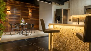 A modern kitchen with a stone backsplash, a stainless steel refrigerator, and a bar area with a high counter.