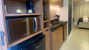 A modern kitchen with wooden cabinets, a black refrigerator, a coffee maker, and a microwave.
