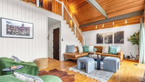 Un vaste espace de vie agrémenté d’un escalier en bois, de canapés en cuir et d’un grand tapis.