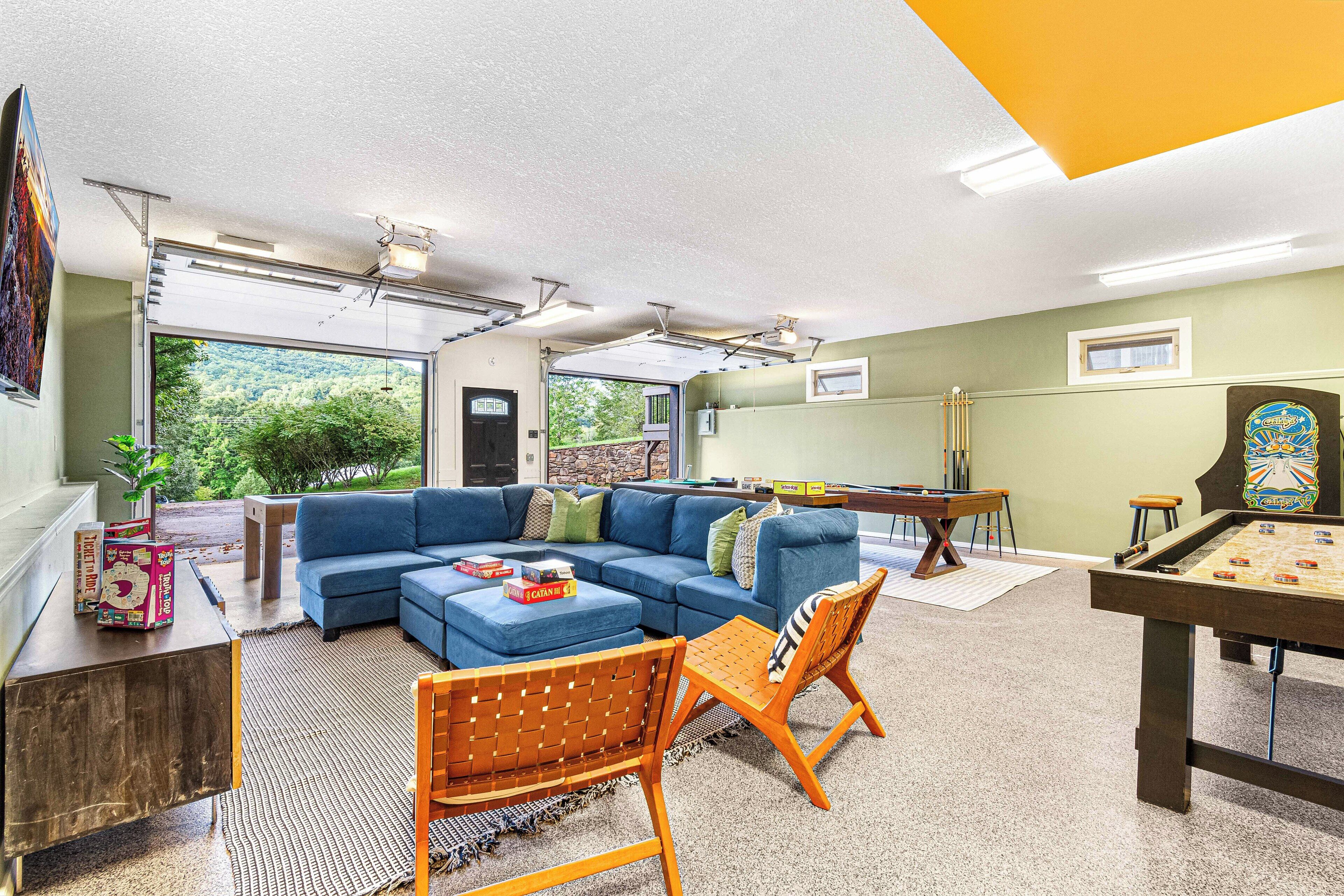 A living room with a blue sectional sofa, a pool table, and a wooden chair.