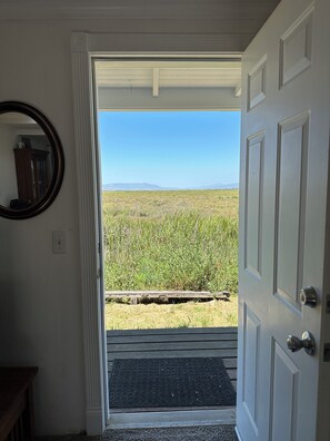 A doorway leading to a grassy field with a clear sky.