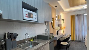 Una cucina moderna con piani di lavoro in granito, un forno a microonde integrato e un lavello. C'è una zona pranzo con tavolo e sedie, e un piccolo tappeto sul pavimento.