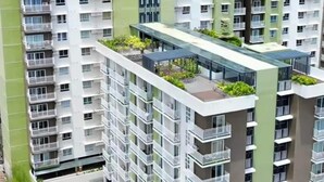 Un edificio residenziale a grattacielo con numerosi balconi, un giardino sul tetto e un'area di parcheggio.