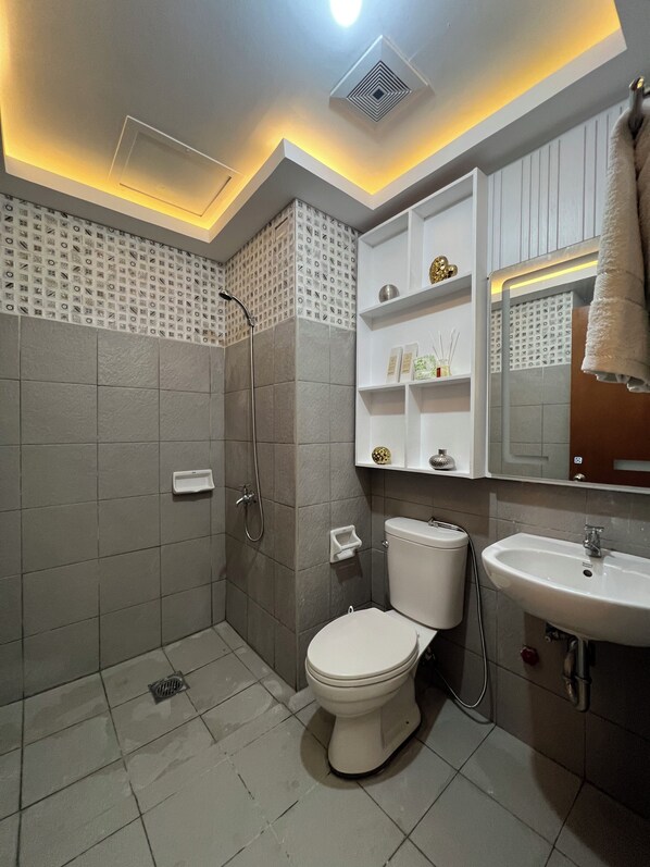 A modern bathroom with a shower, toilet, and sink. - Rinann's Condotel Davao (Davao)