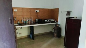 A compact kitchen with a gas stove, a sink, and a refrigerator. - kkrishna apartments (Canacona)