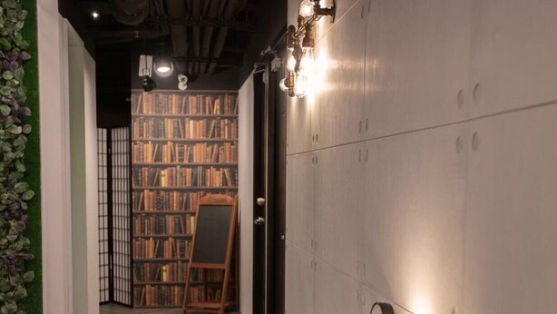 A hallway with a wooden floor, a bookshelf filled with books, and a wooden easel.