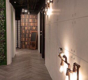 Un couloir doté d’un plancher en bois, d’une bibliothèque remplie de livres et d’un chevalet en bois.