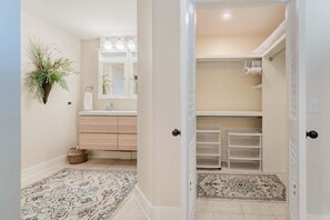 A hallway with a white door, a mirror, a sink, and storage drawers.
