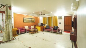 Una sala de estar con una mesa de recepción, sofás rojos, una mesa de centro y un cuadro en la pared.