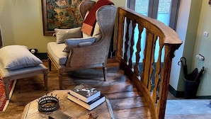 Una sala de estar acogedora con una mesa de centro de madera, un sillón de ratán y un cuadro grande en la pared.