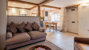 Un salon chaleureux avec un canapé, un coin repas avec une table et des chaises, et une cuisine en arrière-plan.