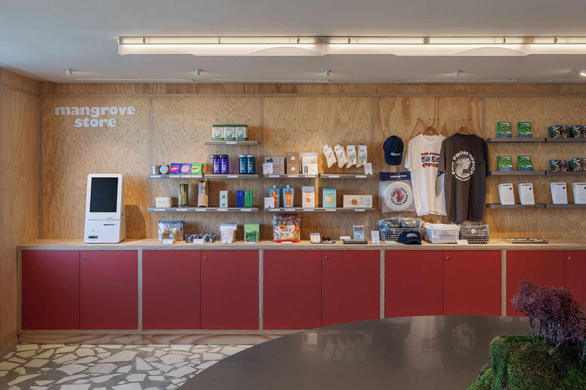 A store interior with wooden walls, a digital kiosk, and shelves stocked with products.