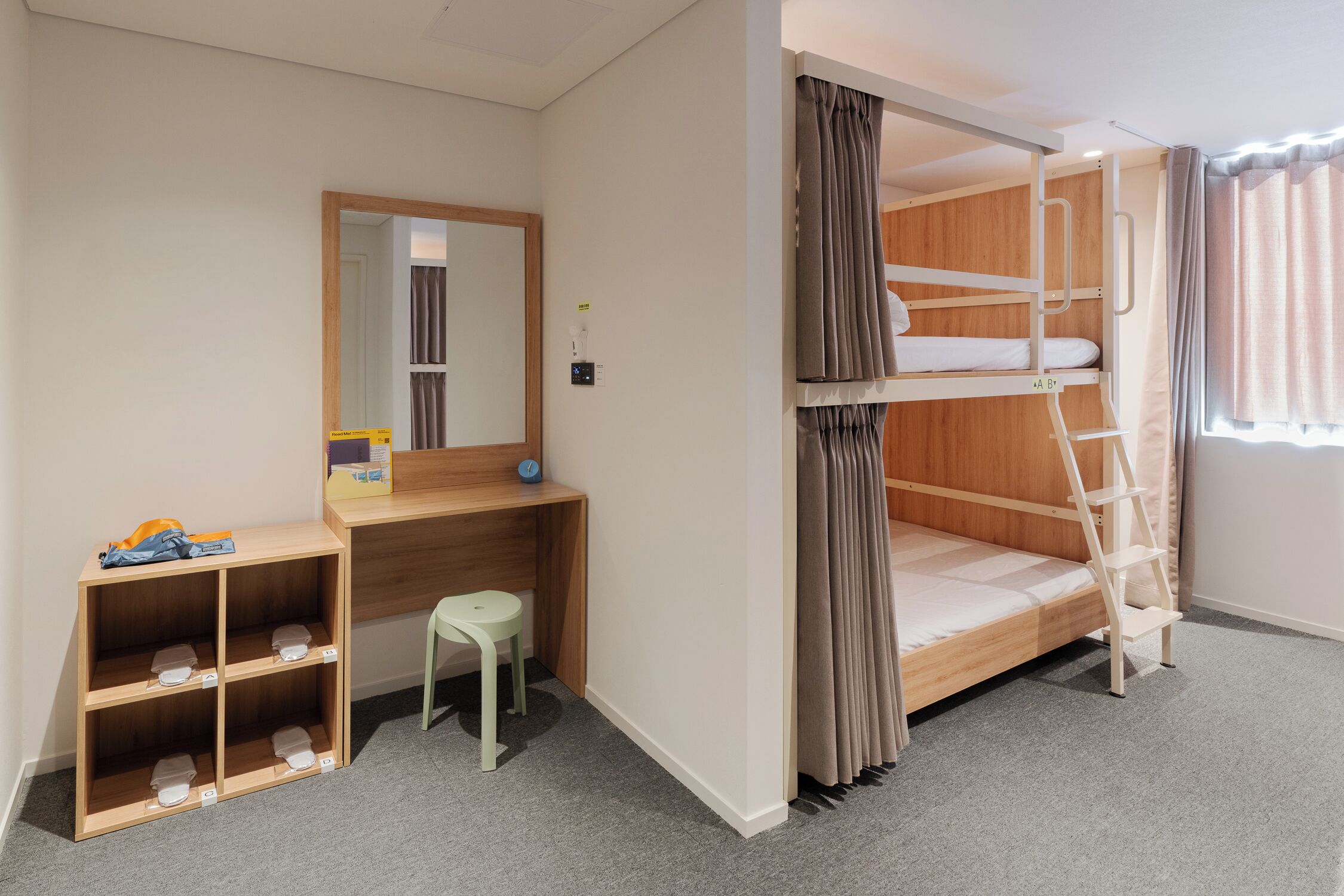 A bunk bed with a ladder, a desk with a chair, and a small stool.