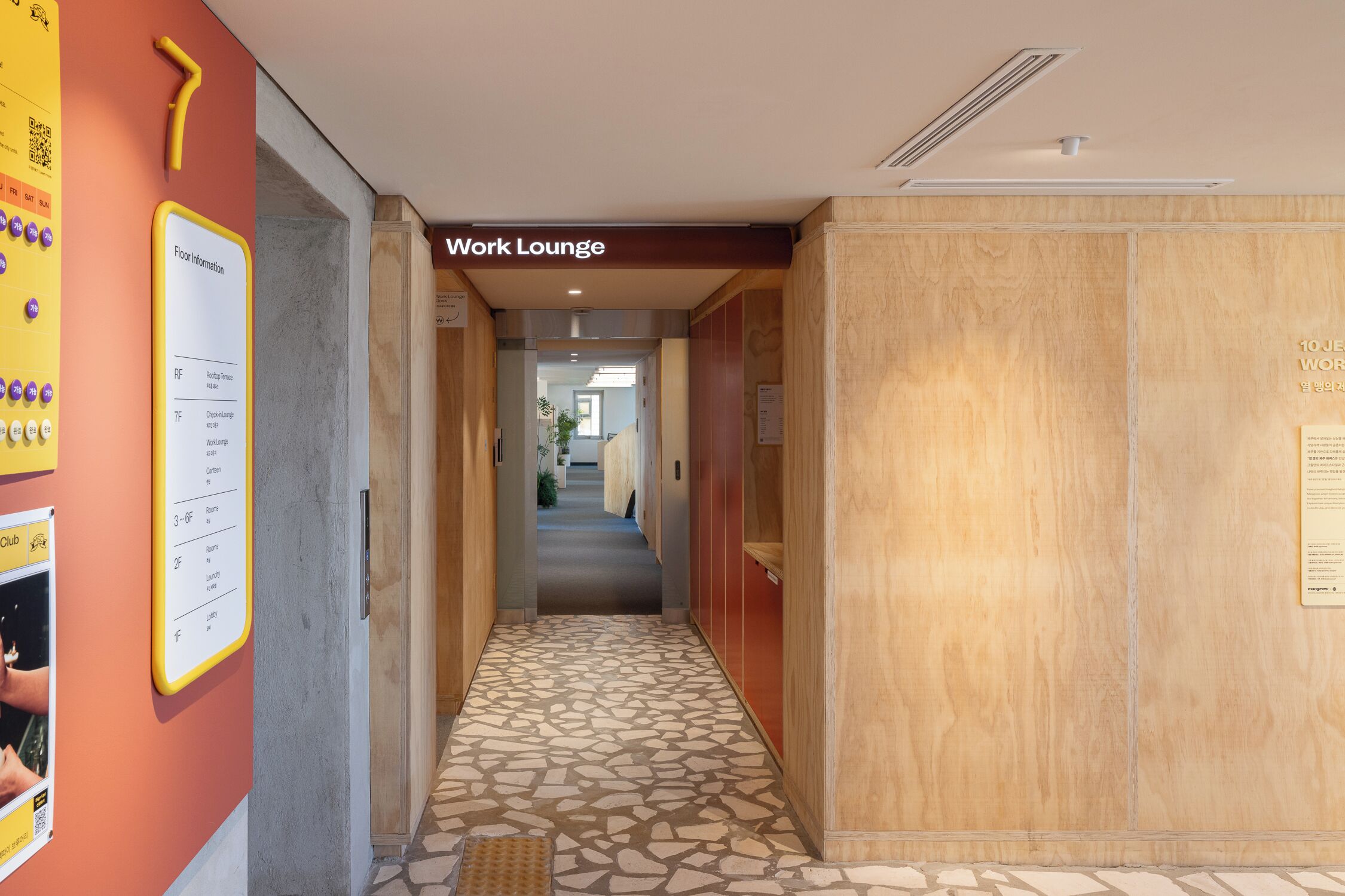 A hallway leading to a work lounge with a tiled floor and wooden walls.