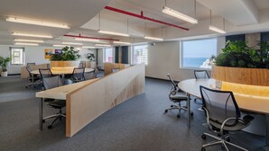 An office space with multiple workstations, a reception area, and large windows offering a view of the sea. - Mangrove Jeju City (Jeju City)