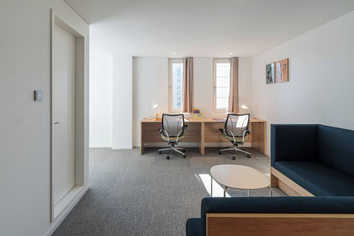 A modern office space with two desks, a sofa, and a small table.