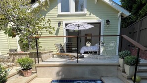 A house with a hot tub in the backyard, a covered patio with outdoor furniture, and a small garden area.