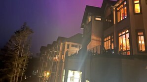 Ein mehrstöckiges Gebäude mit beleuchteten Fenstern bei Nacht, unter einem dunklen Himmel mit sichtbaren Sternen.