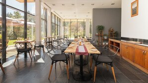 A spacious dining area with large windows, modern chairs, and a wooden table set for a meal. - Zhiwaling Ascent (Thimphu)