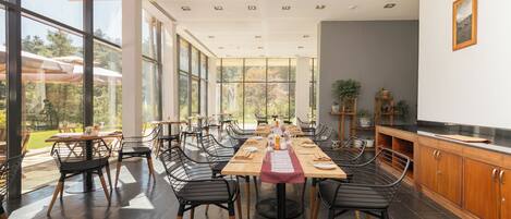 Un amplio comedor con ventanas grandes, sillas modernas y una mesa de madera dispuesta para una comida.