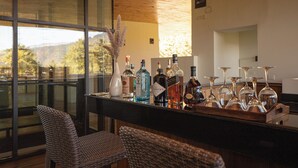 A bar area with wicker chairs, a variety of liquor bottles, and wine glasses. - Zhiwaling Ascent (Thimphu)