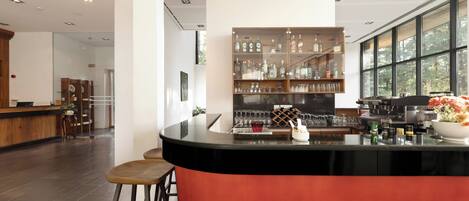 Un espace bar moderne doté d’un comptoir incurvé, de tabourets et d’un meuble à bouteilles.