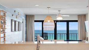 Une cuisine dotée d’une grande fenêtre donnant sur la mer, d’un luminaire suspendu et d’un robinet moderne.