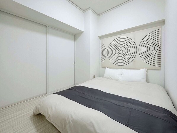 A modern bedroom with a bed, a large artwork on the wall, and a wardrobe.