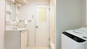 A modern bathroom with a white sink, mirror, and a white washing machine.
