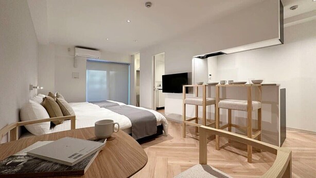 Ein modernes Hotelzimmer mit einem Bett, einem Schreibtisch, einem Sessel, einem Fernseher und einem Fenster.