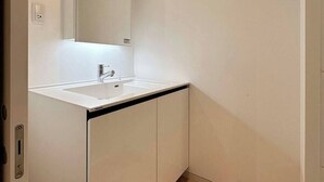 Ein Badezimmer mit einem weißen Waschbecken, einem Spiegel und Holzboden.