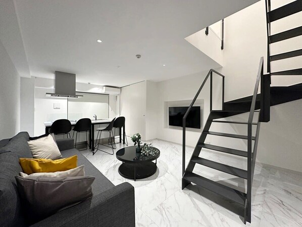 A modern living room with a sofa, coffee table, and a staircase.