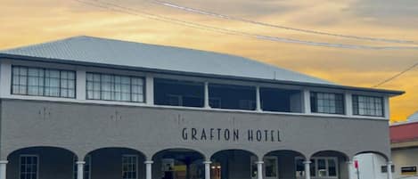 Un edificio de dos plantas con el nombre 'Grafton Hotel' en la fachada, que tiene un techo plano y varias ventanas.