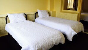 Two single beds with white linens in a room with yellow walls and a window. - Grafton Hotel (Grafton)