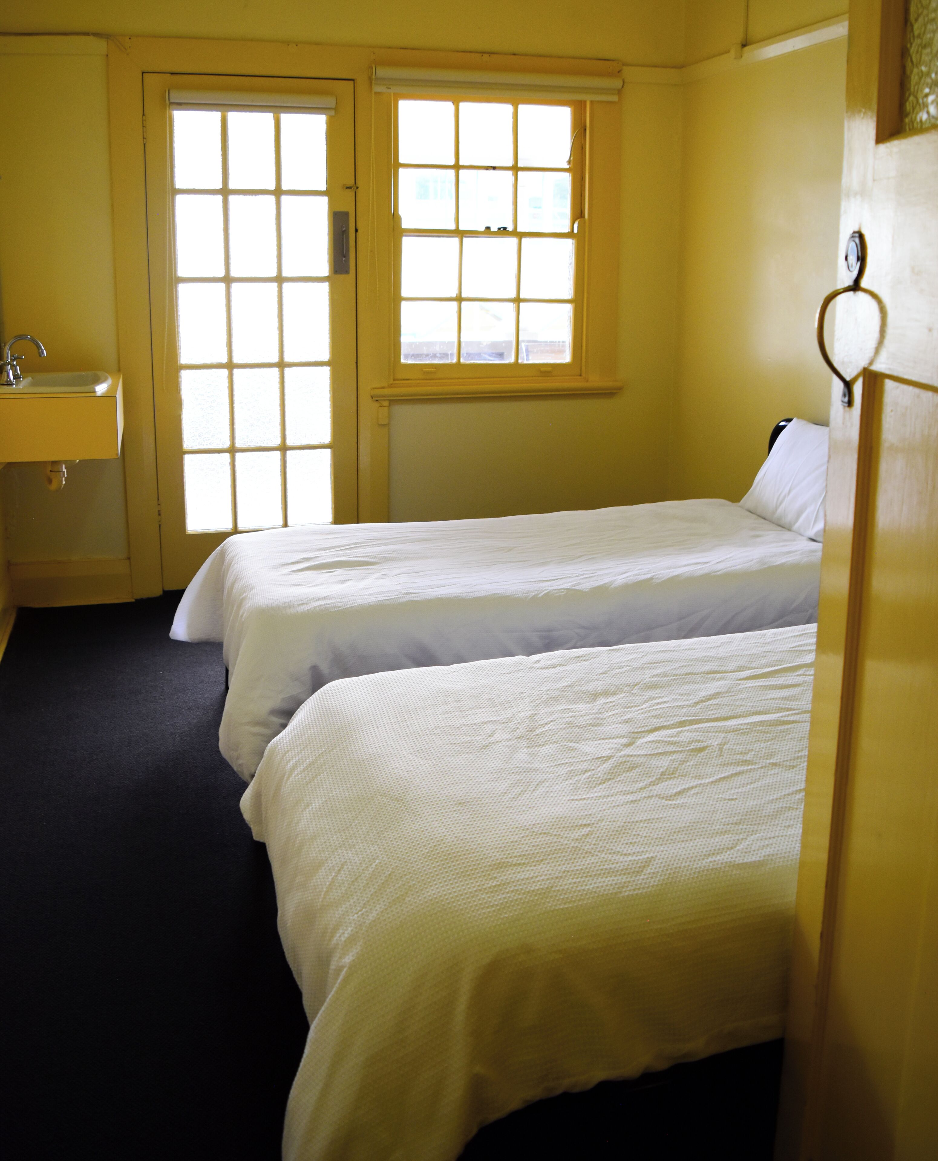 A room with two beds, a sink, and a window.