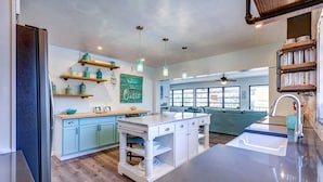 Une cuisine moderne avec des meubles de couleur bleu clair, un îlot central et un coin repas agrémenté d’un canapé bleu.
