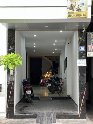 L’entrée d’un hôtel, avec un escalier menant à l’étage supérieur, une enseigne indiquant que l’hôtel se trouve sur la route 30, et un numéro de téléphone pour toute demande de renseignements.
