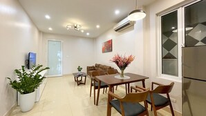 A modern kitchen with a refrigerator, a dining table with chairs, and a potted plant. - NINE HOUSING 30 Yen Hoa (Hanoi)