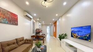 A modern living room with a sofa, a coffee table, a TV, and a dining area with chairs and a table. - NINE HOUSING 30 Yen Hoa (Hanoi)